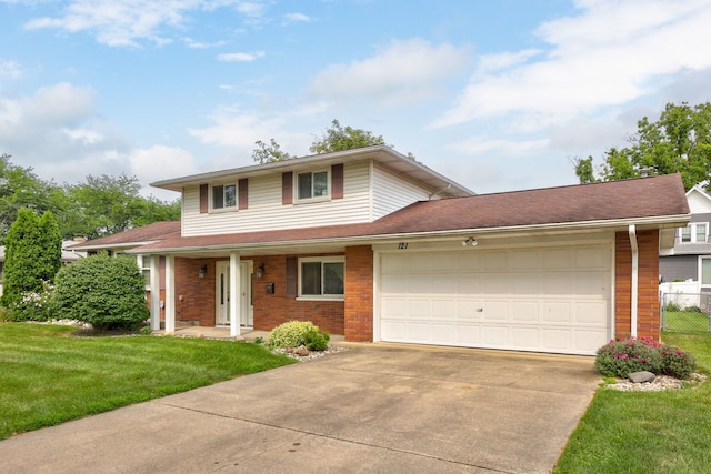 traditional-style home with fence, concrete driveway, a front yard, a garage, and brick siding