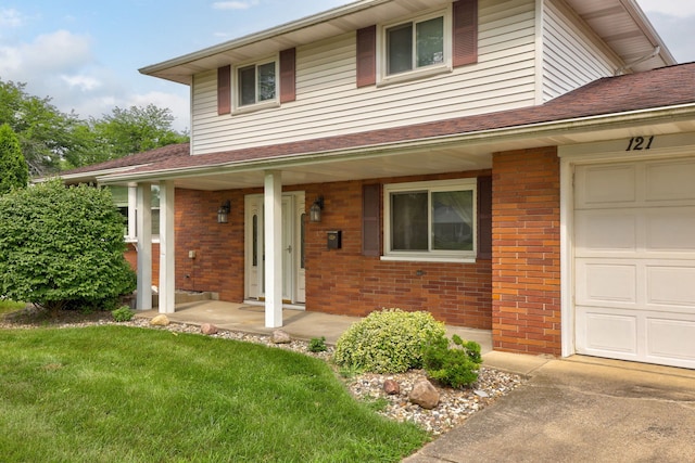 traditional-style home featuring brick siding, covered porch, a front lawn, and a garage