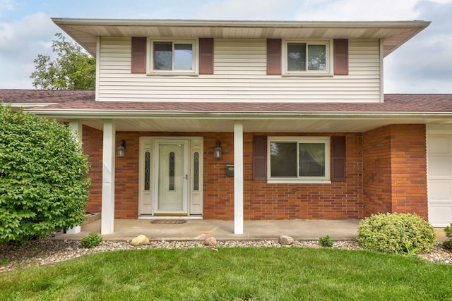 view of front of property featuring an attached garage, brick siding, covered porch, and roof with shingles