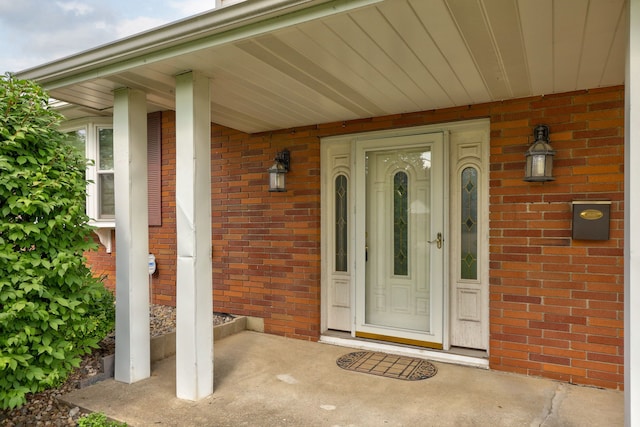 doorway to property featuring brick siding and covered porch