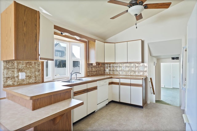 kitchen featuring lofted ceiling, white dishwasher, a sink, decorative backsplash, and light countertops