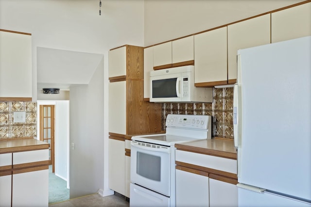 kitchen featuring white appliances, white cabinets, light countertops, and tasteful backsplash