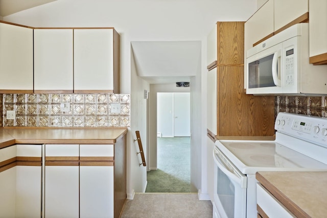 kitchen with white cabinetry, white appliances, light countertops, and light colored carpet