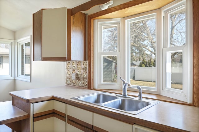 kitchen with a wealth of natural light, tasteful backsplash, light countertops, and a sink