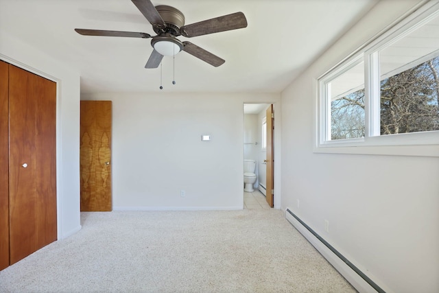 bedroom with ensuite bathroom, a closet, a baseboard radiator, light colored carpet, and ceiling fan