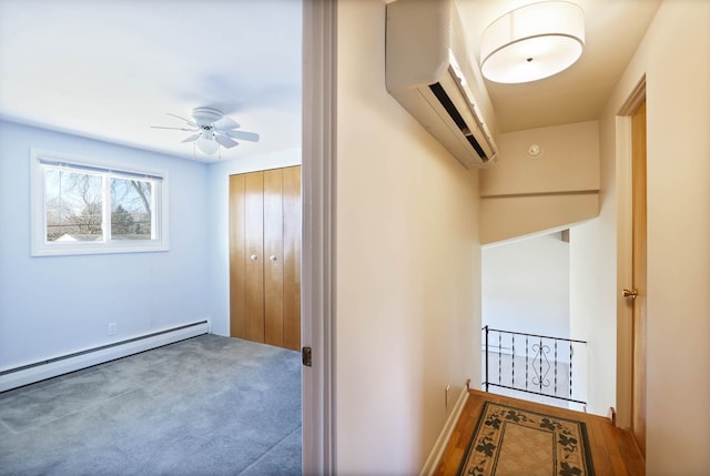 hall with baseboard heating, carpet flooring, and a wall mounted AC