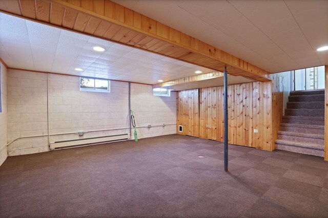 below grade area featuring stairway, wood walls, baseboard heating, recessed lighting, and carpet flooring