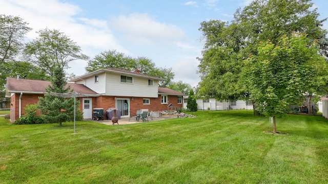 rear view of property featuring a yard, fence, brick siding, and a patio area