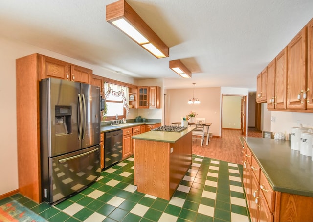 kitchen featuring an inviting chandelier, sink, decorative light fixtures, a kitchen island, and stainless steel appliances