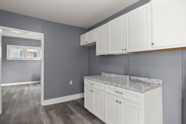 kitchen with white cabinetry, dark wood-type flooring, and light stone counters