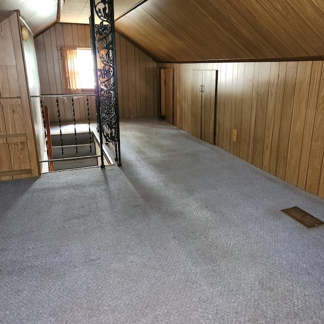 additional living space with wood walls, carpet, wood ceiling, and lofted ceiling