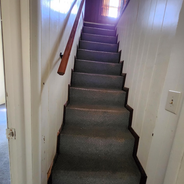 stairs featuring carpet floors and wood walls