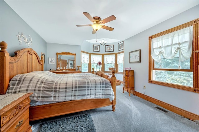 bedroom with ceiling fan with notable chandelier and carpet floors