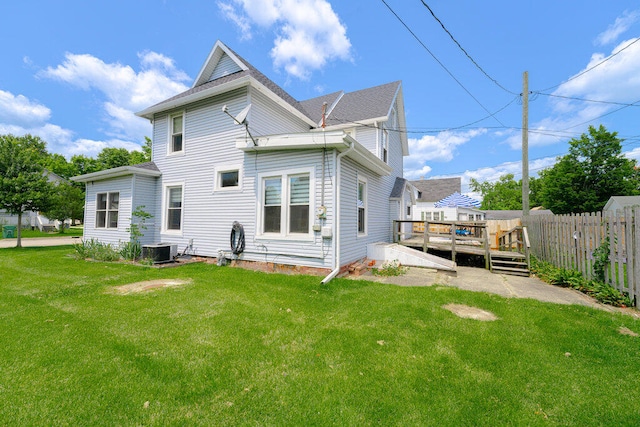 rear view of property featuring a lawn, central AC, and a deck