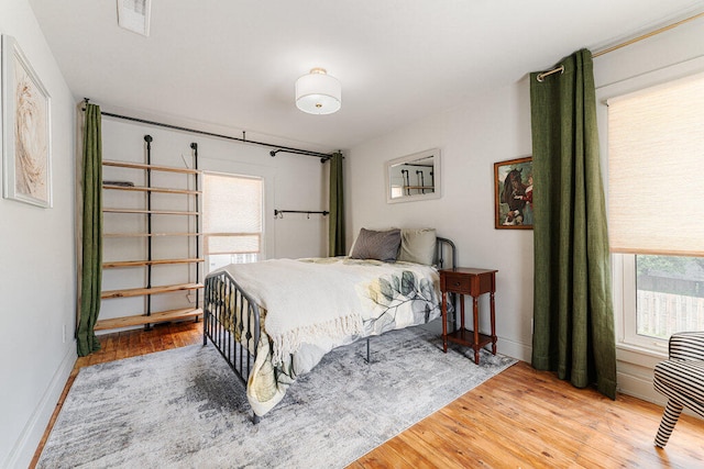 bedroom with multiple windows and hardwood / wood-style floors