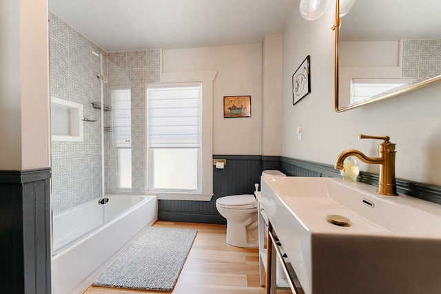 full bathroom with tiled shower / bath, vanity, wood-type flooring, and toilet