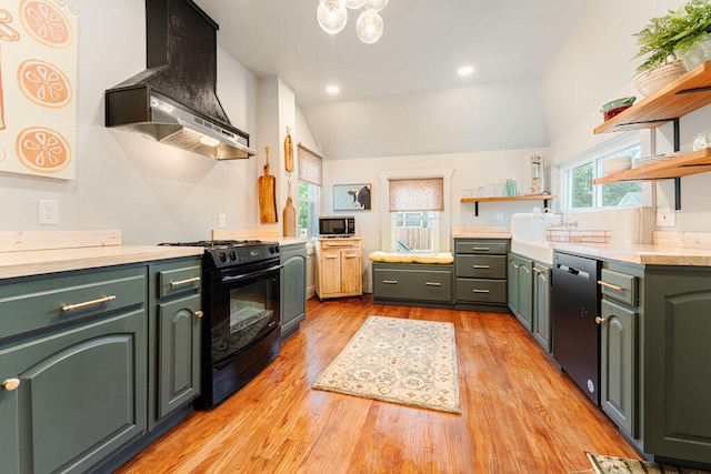 kitchen featuring dishwasher, lofted ceiling, black stove, wall chimney range hood, and light wood-type flooring