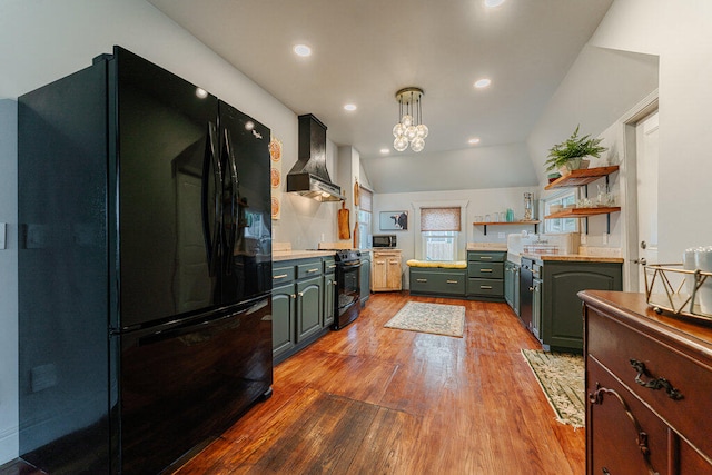 kitchen with wall chimney range hood, pendant lighting, lofted ceiling, black appliances, and light wood-type flooring