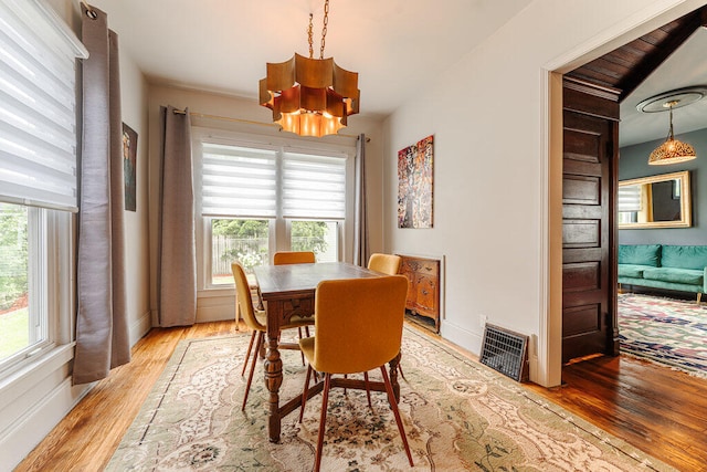 dining area with light hardwood / wood-style floors and a chandelier