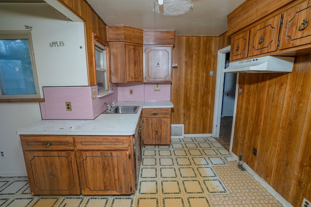 kitchen with tasteful backsplash, wood walls, and sink