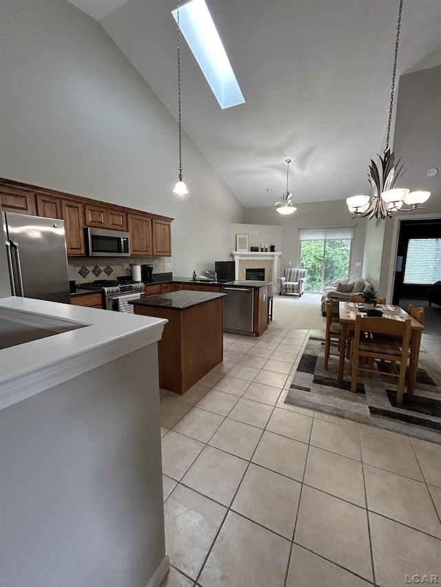 kitchen featuring a chandelier, a kitchen island, backsplash, a fireplace, and appliances with stainless steel finishes