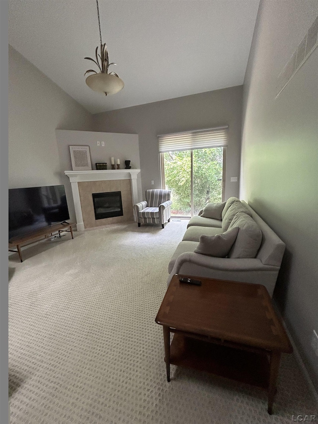 living room featuring lofted ceiling, a tile fireplace, and carpet flooring