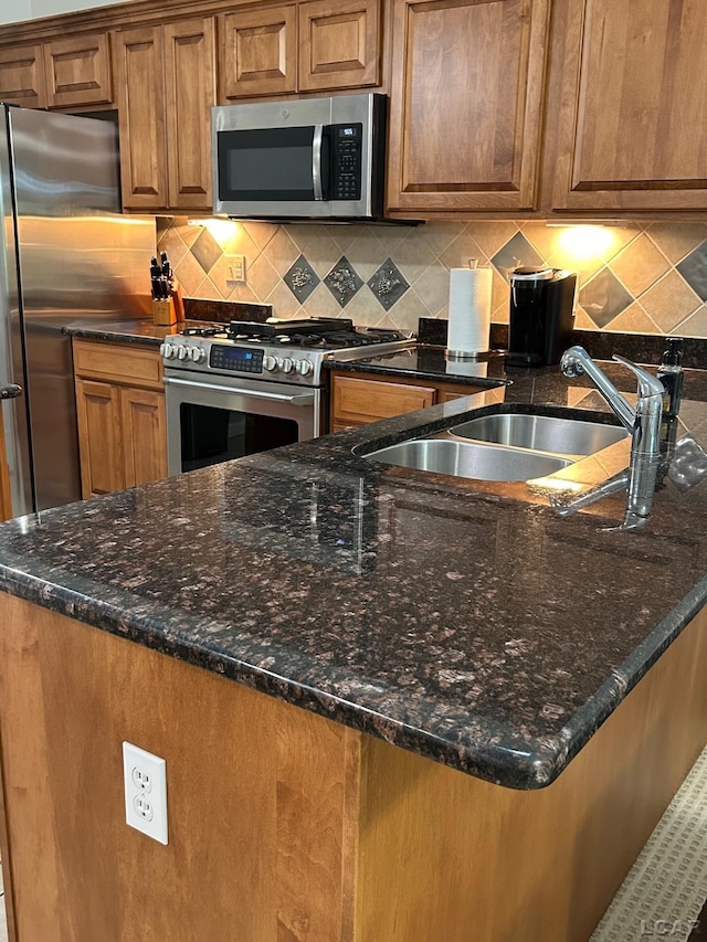 kitchen featuring stainless steel appliances, decorative backsplash, sink, and dark stone counters