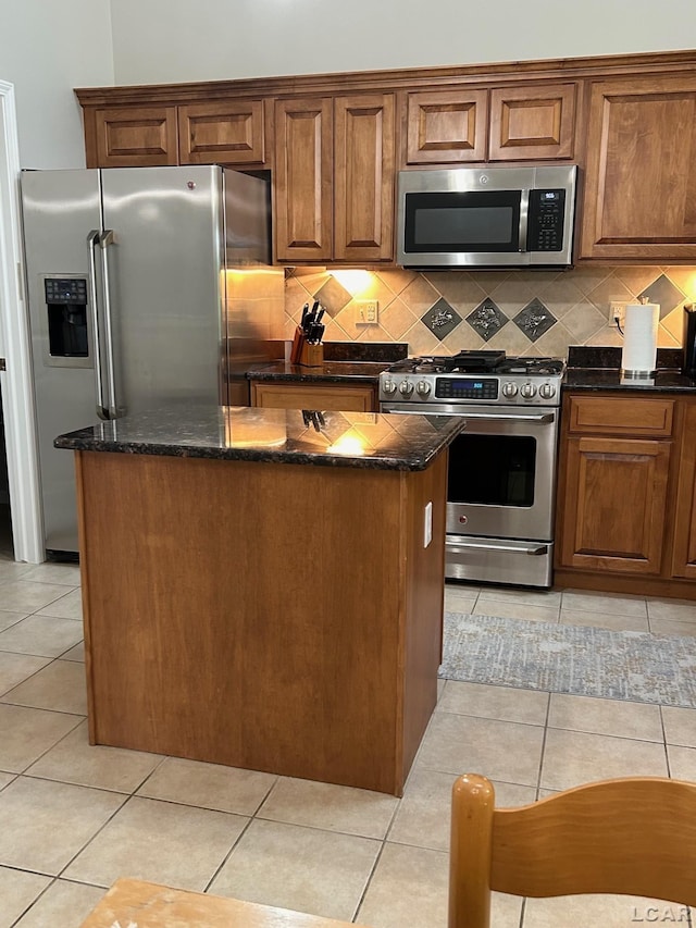 kitchen featuring appliances with stainless steel finishes, dark stone countertops, tasteful backsplash, and light tile patterned floors