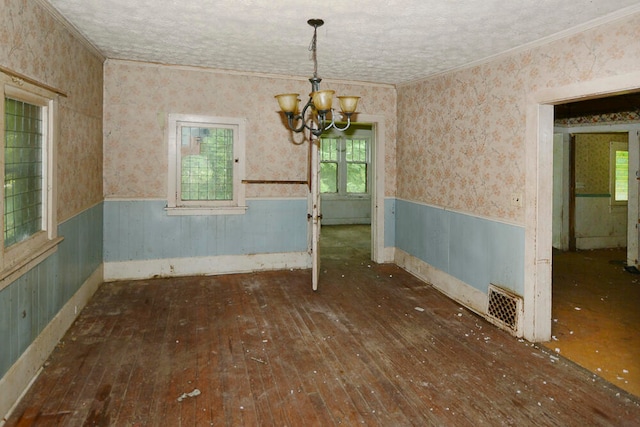 unfurnished dining area featuring dark hardwood / wood-style flooring, a chandelier, and ornamental molding