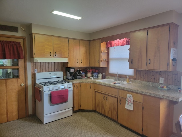 kitchen with white gas range oven, light colored carpet, and sink