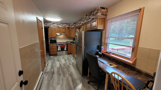 kitchen with light hardwood / wood-style floors, tile walls, stainless steel appliances, and a baseboard radiator