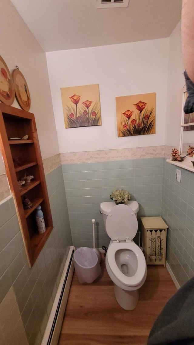 bathroom featuring a baseboard heating unit, toilet, tile walls, and hardwood / wood-style flooring