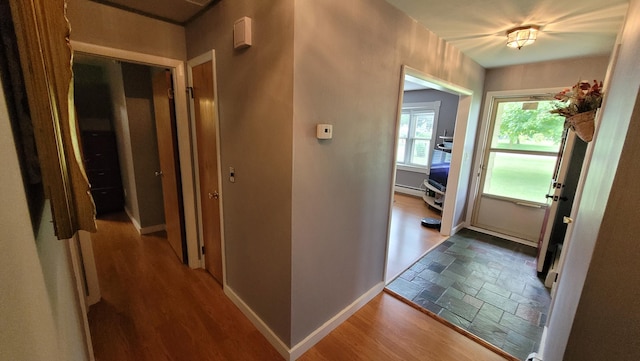 corridor with wood-type flooring and baseboard heating