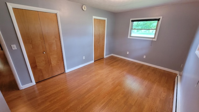 unfurnished bedroom featuring baseboard heating, light hardwood / wood-style floors, and a textured ceiling