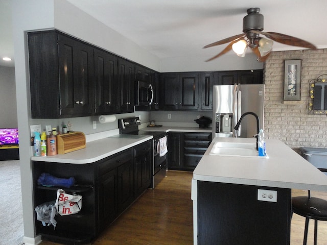 kitchen featuring ceiling fan, sink, dark wood-type flooring, a breakfast bar area, and appliances with stainless steel finishes