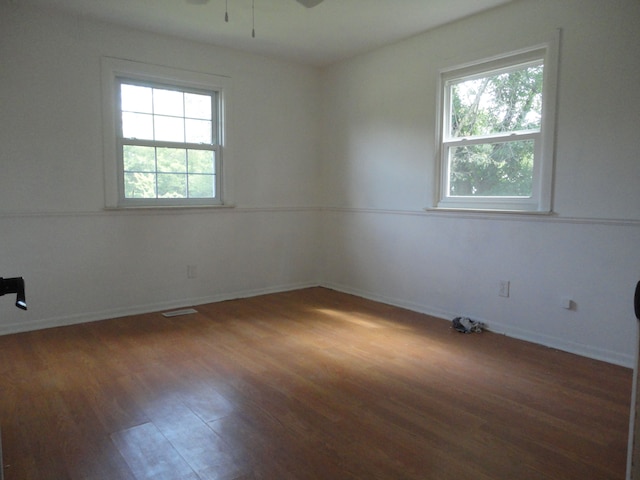 empty room with ceiling fan, a healthy amount of sunlight, and dark hardwood / wood-style floors