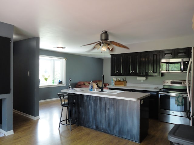 kitchen featuring hardwood / wood-style flooring, sink, stainless steel appliances, and a kitchen island with sink