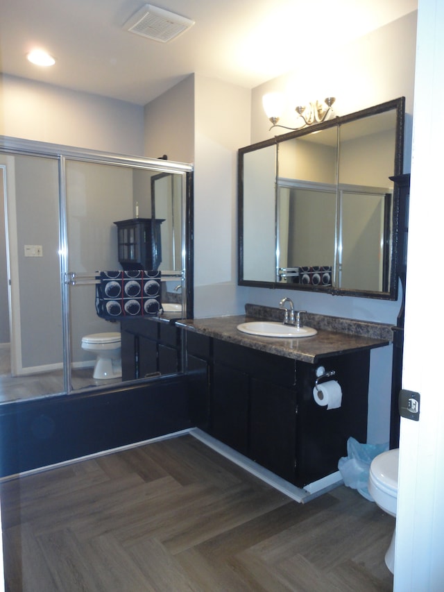 full bathroom with vanity, toilet, parquet floors, and enclosed tub / shower combo