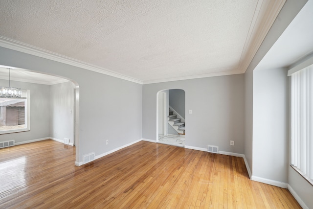 empty room with ornamental molding, a textured ceiling, and hardwood / wood-style flooring