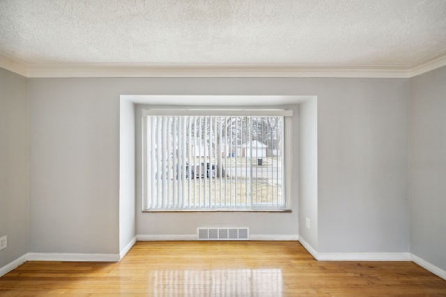 unfurnished room featuring light wood-type flooring, a textured ceiling, and ornamental molding