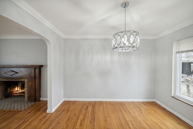 unfurnished dining area featuring an inviting chandelier, light hardwood / wood-style flooring, a wealth of natural light, and ornamental molding