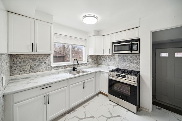 kitchen featuring light stone countertops, appliances with stainless steel finishes, tasteful backsplash, sink, and white cabinets