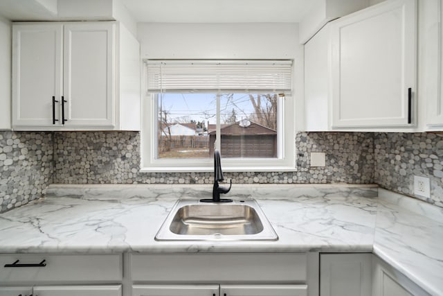 kitchen with white cabinets, sink, and tasteful backsplash