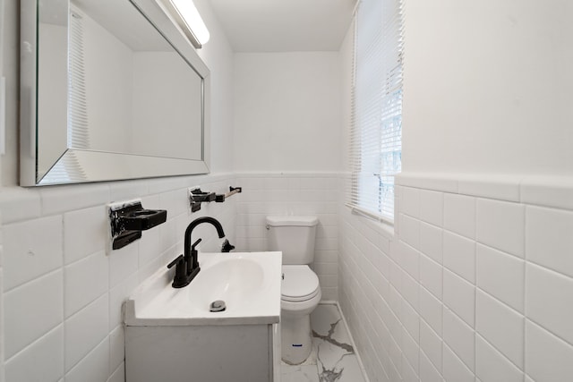 bathroom with vanity, toilet, and tile walls