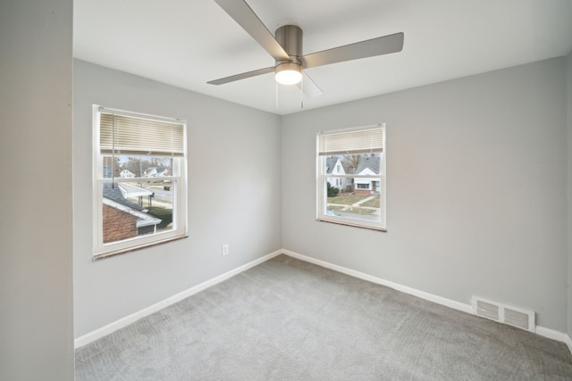 carpeted spare room featuring a wealth of natural light and ceiling fan