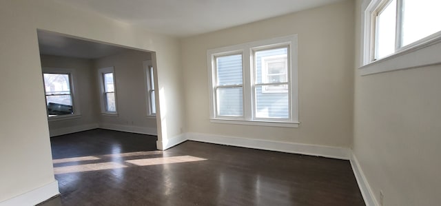 spare room featuring a wealth of natural light and dark wood-type flooring