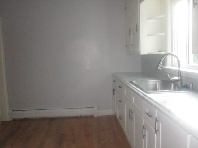 kitchen featuring white cabinets, dark hardwood / wood-style flooring, a baseboard heating unit, and sink