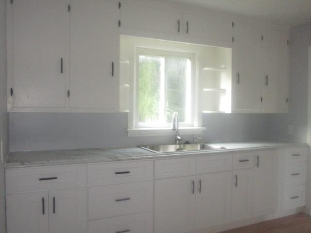 kitchen with white cabinets, light stone counters, and sink