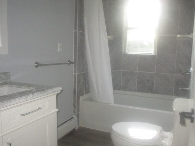 full bathroom with a baseboard heating unit, vanity, toilet, and shower / bath combo with shower curtain