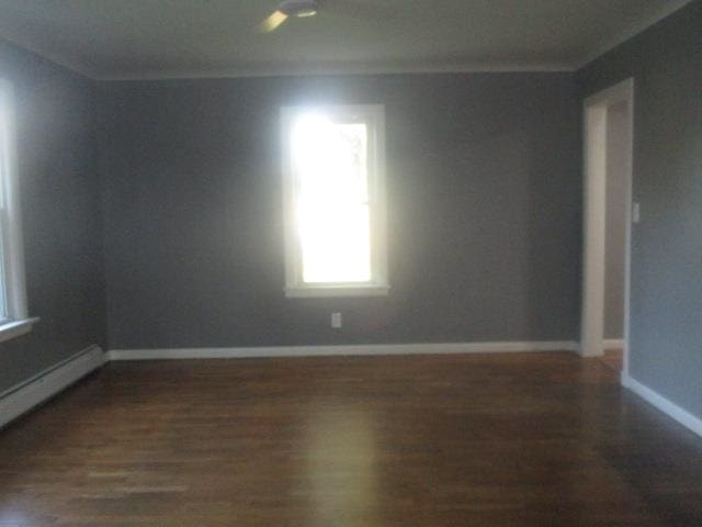 empty room with dark wood-type flooring and a baseboard radiator